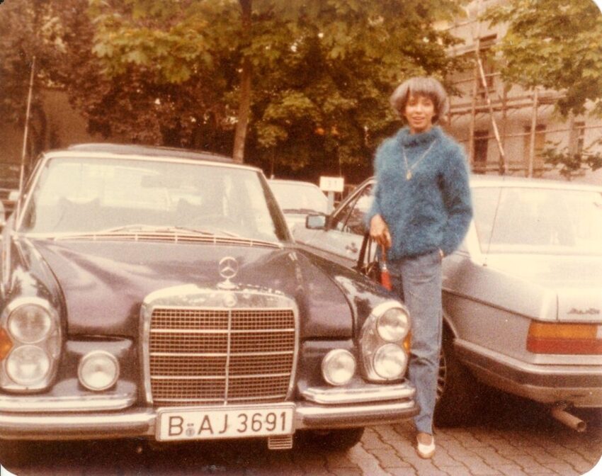 Download the full-sized image of A Photograph of Marlow Monique Dickson Standing Next to a Car