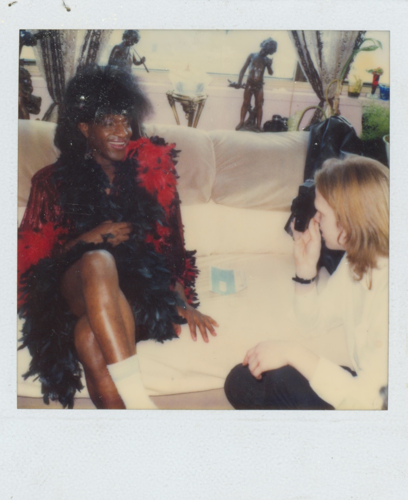 Download the full-sized image of A Photograph of Marsha P. Johnson Posing for a Camera in a Black and Red Feathered Dress